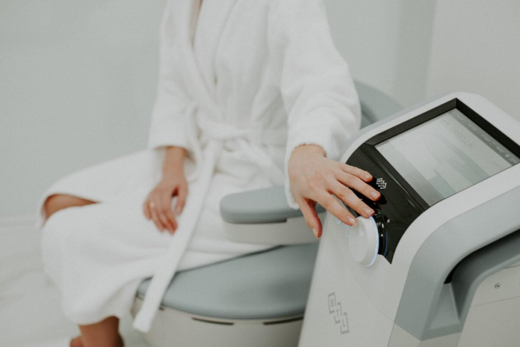 A person in a white robe using a medical device in a clinical setting.